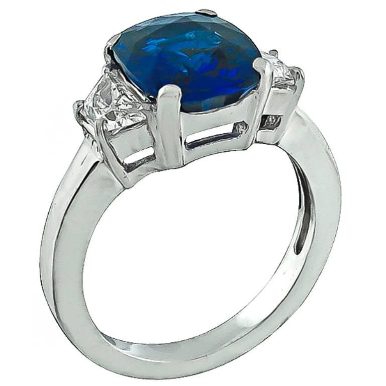 This fabulous platinum engagement ring is centered with a high quality cushion cut Ceylon sapphire that weighs 3.01ct. The center stone is flanked by sparkling trapezoid cut diamonds that weigh approximately 0.60ct. graded G-H color with VS clarity.