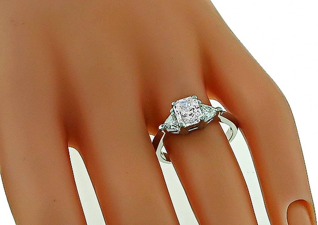 This fabulous 14k white gold engagement ring is centered with sparkling GIA certified radiant cut diamond that weighs 0.97ct. graded H color with SI1 clarity. The center stone is flanked by two dazzling trilliant cut diamonds that weigh