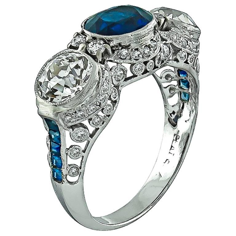 This amazing platinum ring is centered with a natural oval cut sapphire that weighs approximately 1.50ct. The sapphire is flanked by two old mine cut diamonds weighing approximately 1.80ct and smaller old mine diamonds weighing approximately 0.50ct.