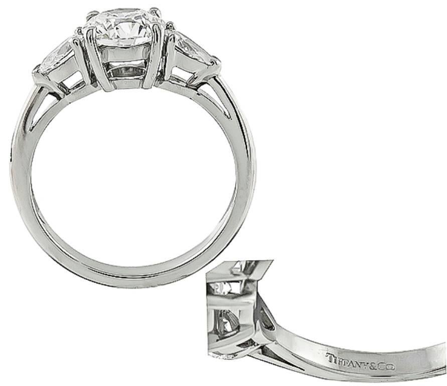 This stunning platinum engagement ring by Tiffany & Co, is centered with a sparkling round cut diamond that weighs 1.24ct. graded G color with VVS1 clarity. Accentuating the center stone are dazzling pear shape diamonds that weigh approximately