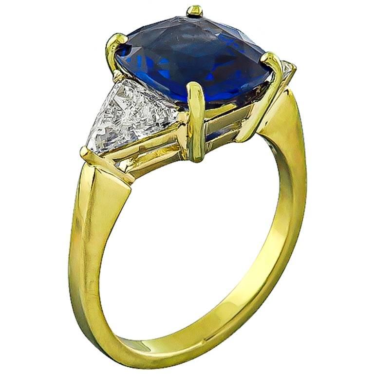 This amazing 18k yellow ring is centered with a high quality cushion cut sapphire that weighs 3.98ct. The sapphire is accentuated by sparkling trilliant cut diamonds that weigh approximately 1.00ct. graded G color with SI2 clarity. The top of the