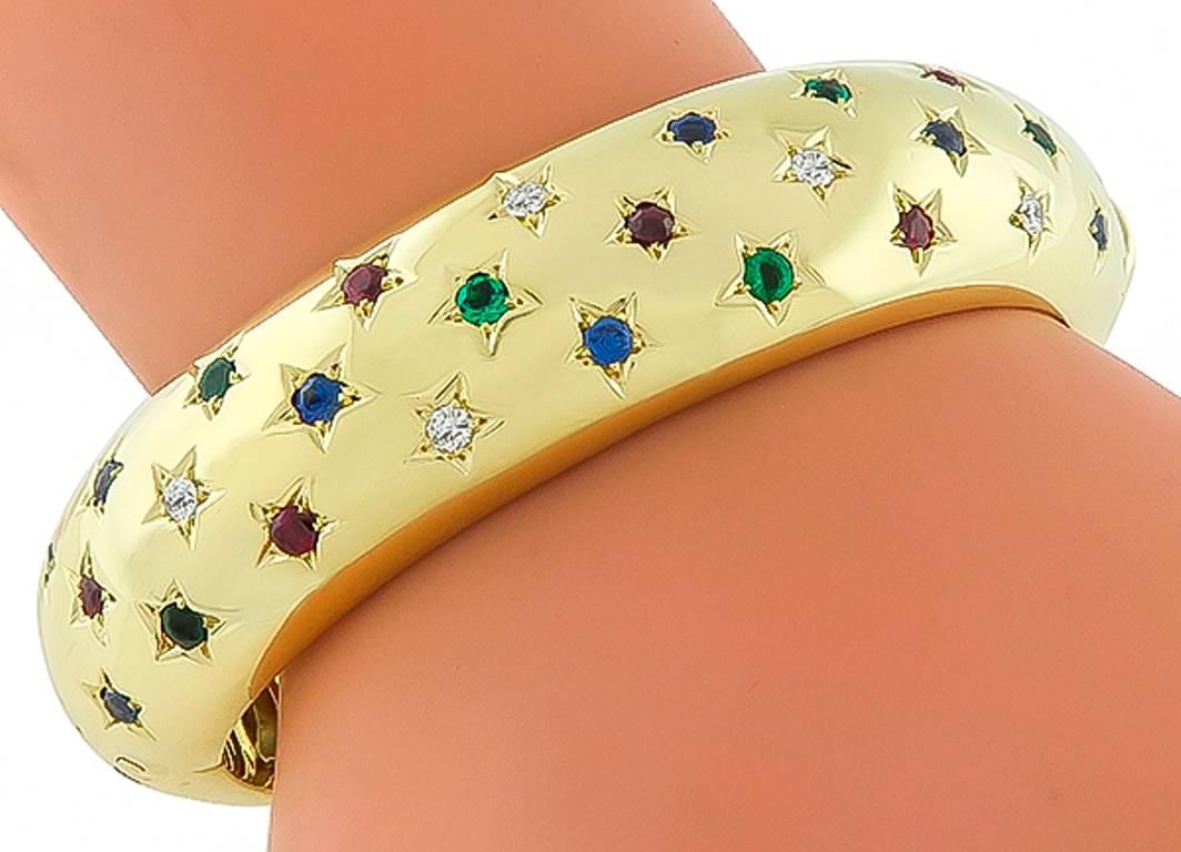 This fabulous 18k yellow gold bangle is set with round cut multi color stones which are diamond, emerald, ruby and sapphire. The bangle measures 17mm in width and will fit a standard wrist size. It is stamped 750 and weighs 64.3 grams.

Inventory