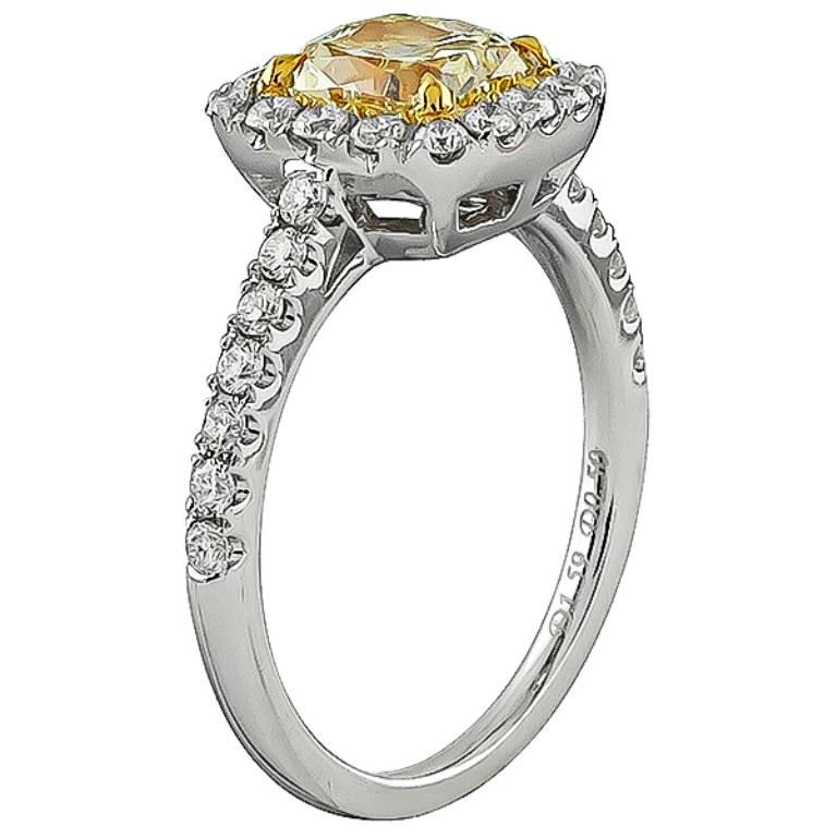 This amazing 18k white gold engagement ring is centered with a lovely radiant cut natural fancy yellow diamond that weighs 1.59ct. The clarity of the diamond is VS1. Accentuating the center stone sparkling round cut diamonds that weigh approximately