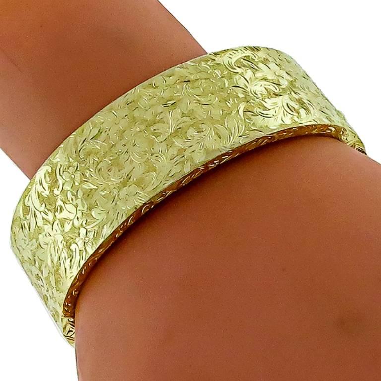 Made of 14k yellow gold, this bangle bracelet features a floral gilded design. It measures 22mm in width and weighs 42.5 grams. The bracelet is stamped 585 14ct AUSTRIA and will fit a standard wrist size.

Inventory #63654PRBS