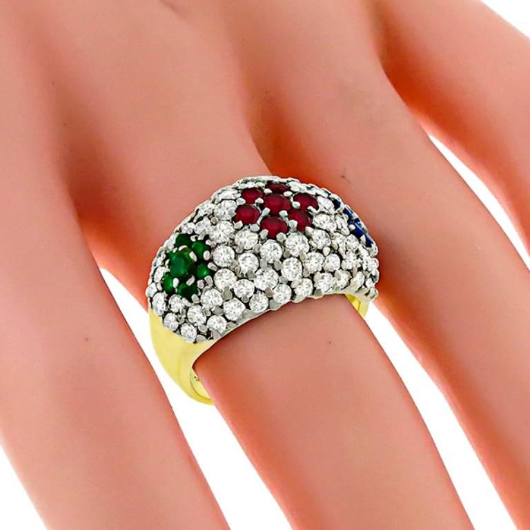 This beautiful 18k yellow gold ring features round cut diamonds weighing approximately 1.50ct graded H color with VS clarity. Accentuating the diamonds are round cut rubies, emeralds and sapphires that weighs approximately  0.25ct, 0.50ct and
