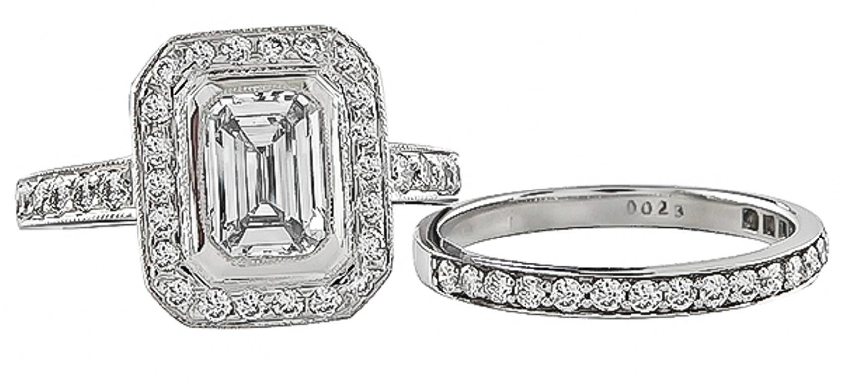 This stunning 18k white gold engagement ring centers a sparkling GIA certified emerald cut diamond that weighs 1.01ct. graded G color with VVS2 clarity. The center diamond and the wedding band is accentuated by dazzling round cut diamonds that weigh