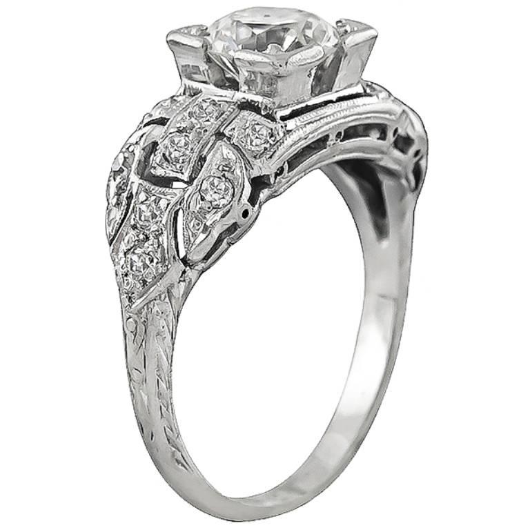 This magnificent platinum engagement ring from the Art Deco era, is centered with a sparkling round cut diamond that weighs 0.85ct. graded H-I color with SI1 clarity. Accentuating the center stone are dazzling round cut diamonds that weigh