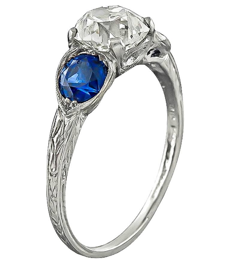 Made of platinum, this ring is centered with a sparkling GIA certified old mine brilliant cut diamond that weighs 1.39ct. graded K color with VS2 clarity. The center diamond is flanked by high quality round cut sapphires that weigh approximately