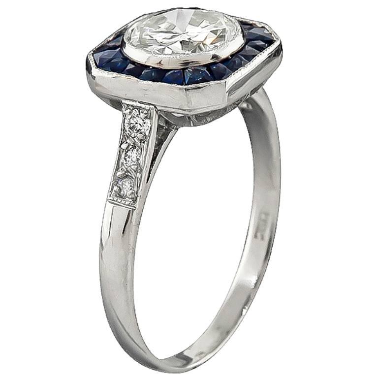 This fabulous platinum ring is centered with a sparkling GIA certified round brilliant cut diamond that weighs 1.06ct. graded L color with VS2 clarity. Accentuating the center stone are high quality even colored sapphires and sparkling diamond