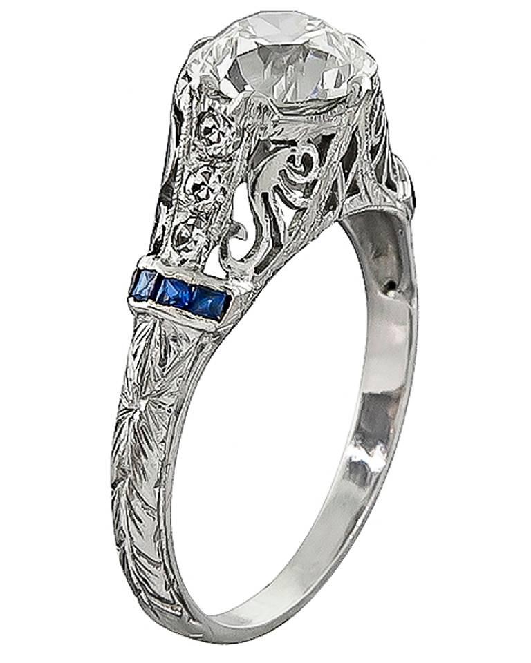 This fabulous platinum engagement ring from the Art Deco era, is centered with a sparkling GIA certified old mine cut diamond that weighs 1.59ct. graded J color with VS1 clarity. Accentuating the center stone are lovely sapphire and diamond accents.