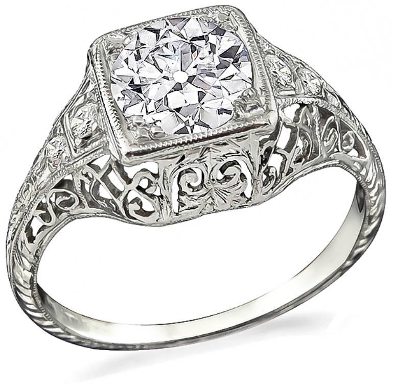 This wonderful platinum engagement ring from the Edwardian era, is centered with a sparkling GIA certified old European cut diamond that weighs 1.00ct. graded H color with VS2 clarity. The ring has impressive engravings and open work design. 
It is