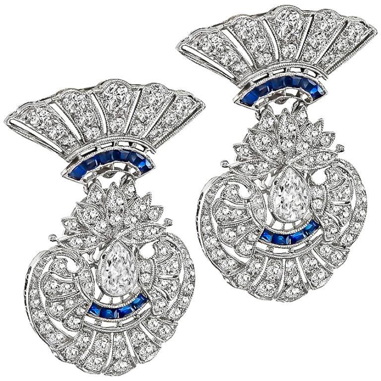 This fabulous pair of platinum earrings from the Art Deco era, features sparkling pear and round cut diamonds that weigh approximately 5.00ct. graded G color with VS clarity. The diamonds are accentuated by even colored sapphire accents. The