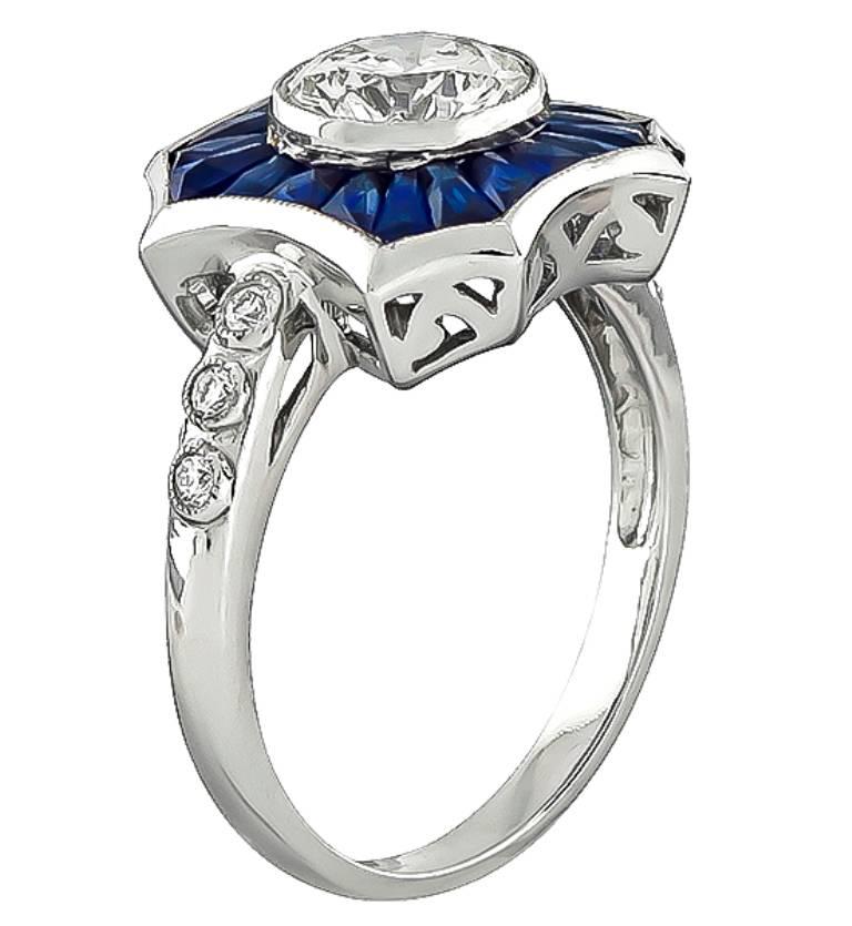 This stunning 18k white gold engagement ring is centered with a sparkling round cut diamond that weighs 1.20ct. graded I-J color with SI1 clarity. The center diamond is accentuated by sapphire and diamond accents. The ring is stamped 750 and weighs