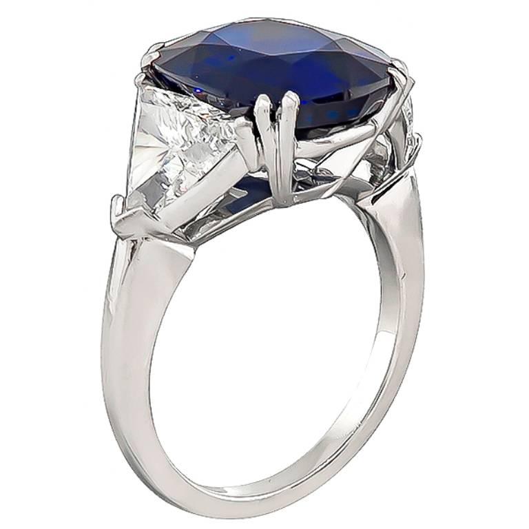 This stunning platinum engagement ring is centered with a lovely cushion cut sapphire that weighs 7.17ct. The sapphire is accentuated by sparkling trilliant cut diamonds that weigh 1.61ct. graded I color with VS2-SI1 clarity. The top of the ring