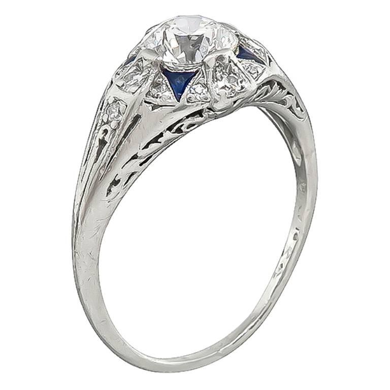 This elegant platinum engagement ring from the Art Deco era, is centered with a sparkling GIA certified old mine cut diamond that weighs 0.86ct. graded E color with VS1 clarity. Accentuating the center stone are sapphire and diamond accents. The