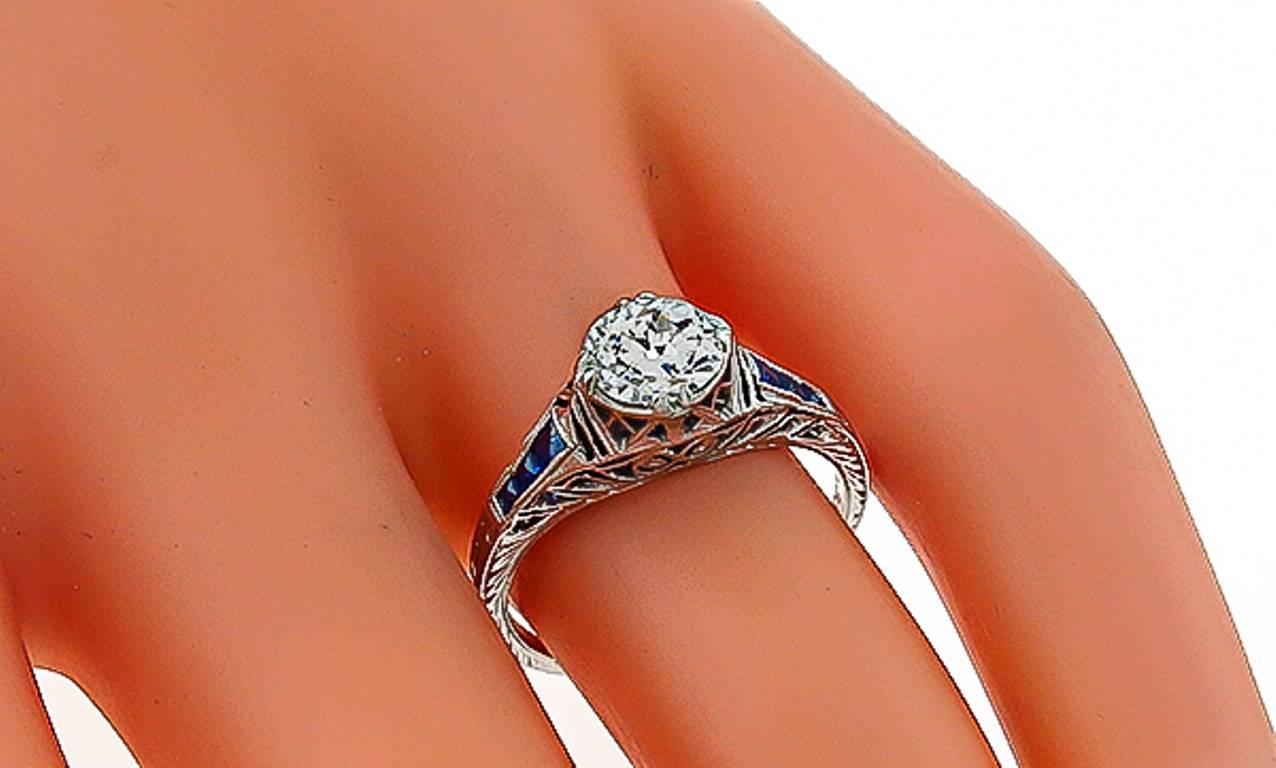This magnificent platinum ring from the Art Deco era, centers a sparkling GIA certified old mine cut diamond that weighs 0.92ct. graded J color with VS2 clarity. The center diamond is accentuated by vivid blue sapphire accents. 
The ring is size 6,