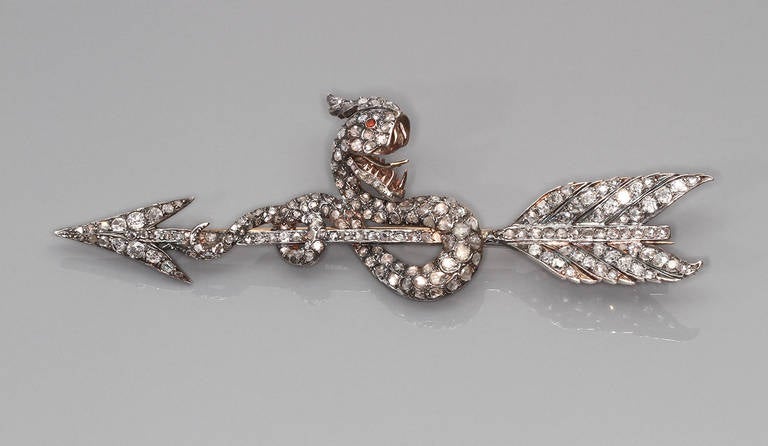 Shaped like a stylized snake coiled around an arrow, this brooch is very similar in size and design to one made by Oscar Massin in 1878.

Oscar Massin (1829-1892) was one of the most innovative jewelers of the late 19th century having produced