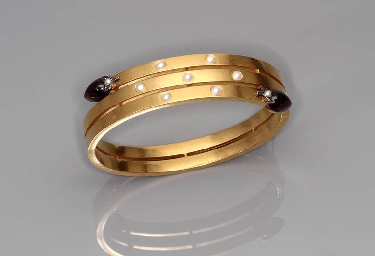 A bangle in gold encrusted with tiny pearls and pear-cut garnet ends

Paris assay marks, 1941

Inside diameter approximately 5,5 cm

Measurements: 1,5 cm wide at its largest point