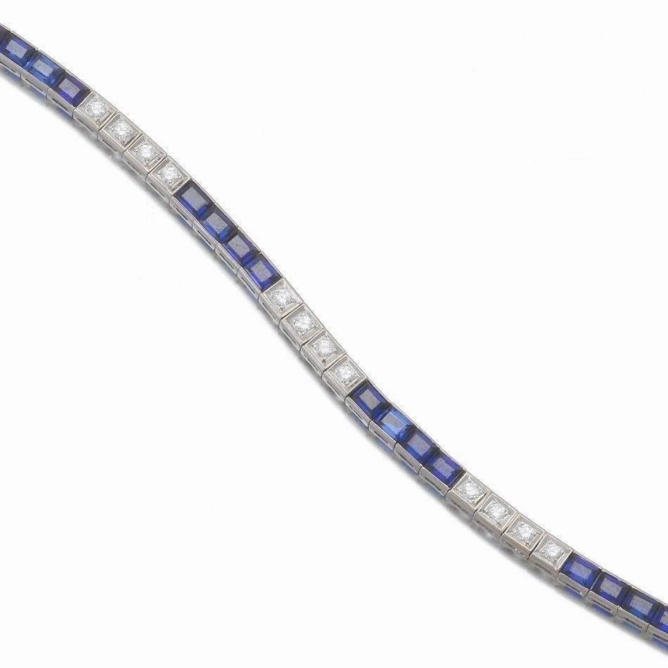 Stunning 1930's Art Deco H-I/VS Diamond 14K Gold Synthetic Sapphire Line Tennis Bracelet.   The bracelet has a slide-in clasp and safety catch, set with 20 rectangular cut blue sapphires, approximately 8 carats and with 20 round brilliant cut