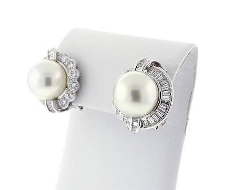 These rare South Seas pearl & diamond earrings each bear a beautiful large South Seas pearl measuring 14.8mm, surrounded by approximately 1.30 carats of brilliant round cut and baguette style G-H/VS diamonds.  Total diamond weight for the