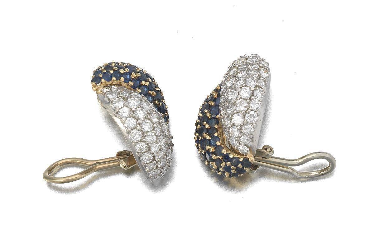 Beautiful 18 Karat Gold (white and yellow) earrings in a double elongated bombe shape, set with round brilliant cut diamonds on one side, (total estimated diamond weight 3.0 cttw), and blue sapphires on the other, total estimated sapphire weight 3.0