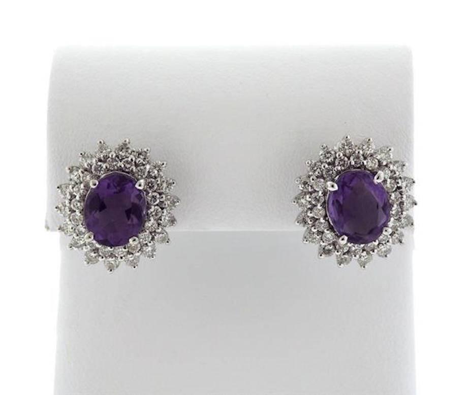 Stunning earrings composed of 18k gold and set with stunning amethyst gemstones measuring 1.54 carats in both the left and right. Surrounding the amethyst stones are double halos of G-H VS quality brilliant cut diamonds totaling 1.80 carats. The