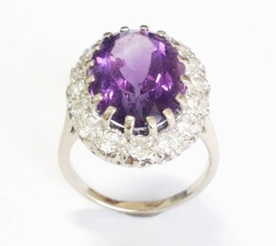 Lovely 14K white gold amethyst and diamond cocktail ring contains one center oval amethyst weighing approximately 10.00 carats.  Set in a halo effect around the amethyst are 16 round brilliant diamonds totaling approximately 1.00 carat of H/VS