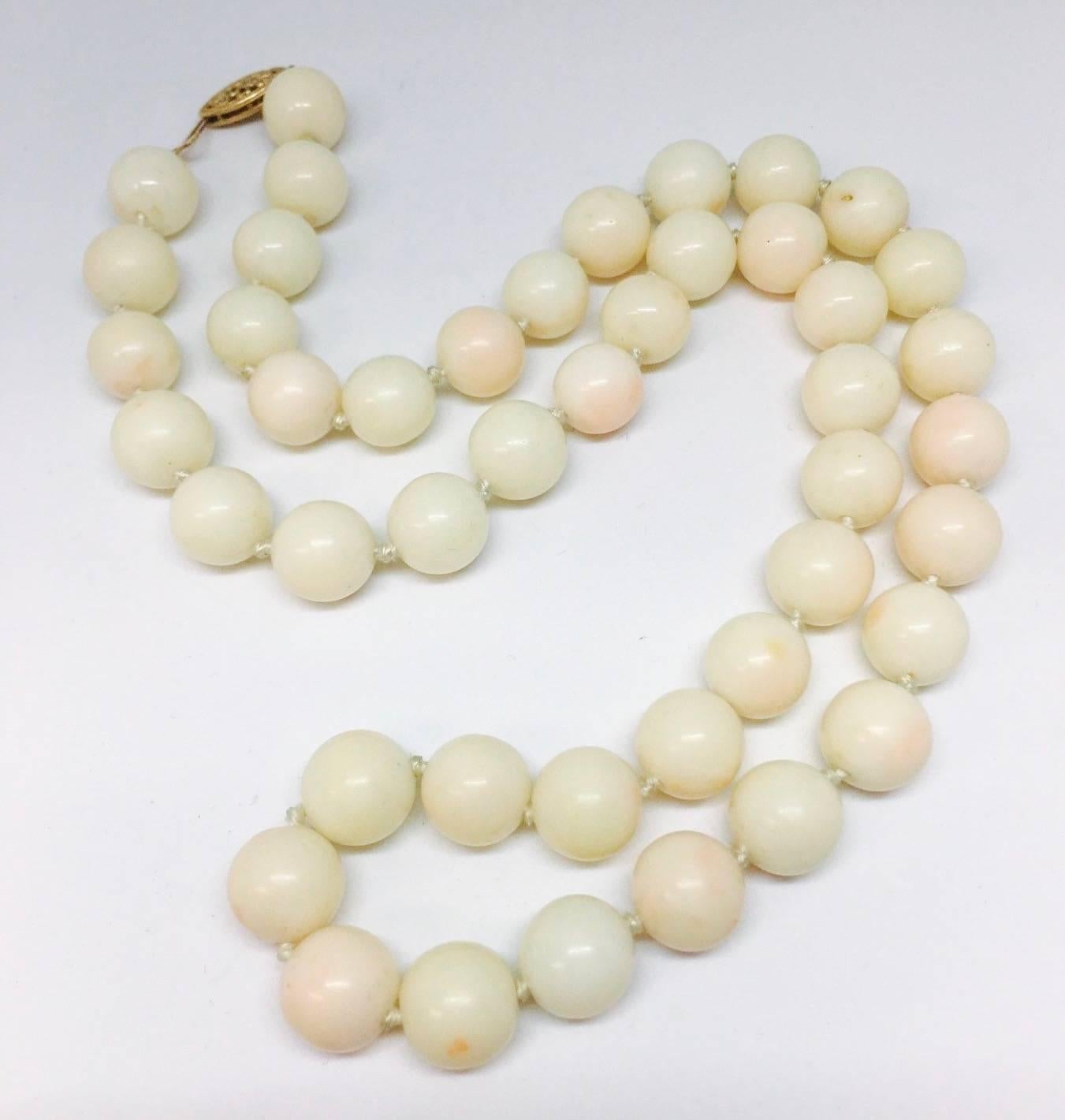 Beautiful 14k gold angel skin coral beaded necklace set with sizable 10mm beads and reaching a princess length of approximately 20".  A striking necklace on the neck, this beautiful strand of pale peachy pink coral beads features natural