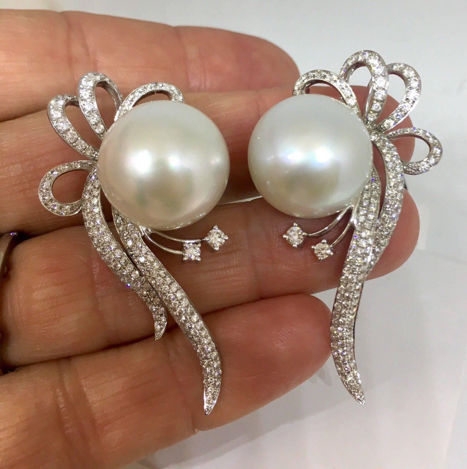 Stunning estate large 18K white gold earrings featuring 3.56 carats of round brilliant diamonds and white, near round cultured pearls with posts and omega back closures.  These beautiful large pearls are set in a white 18K gold bow draped frame, set