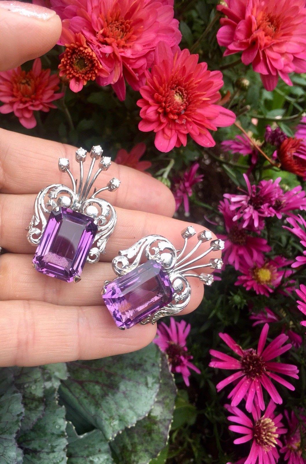 These beautiful retro double clips are set in 18 karat white gold with two outstanding emerald cut amethyst stones and high clarity diamonds.  These can be used as an accessory on a cocktail dress straps or blazer collars, and they could also be