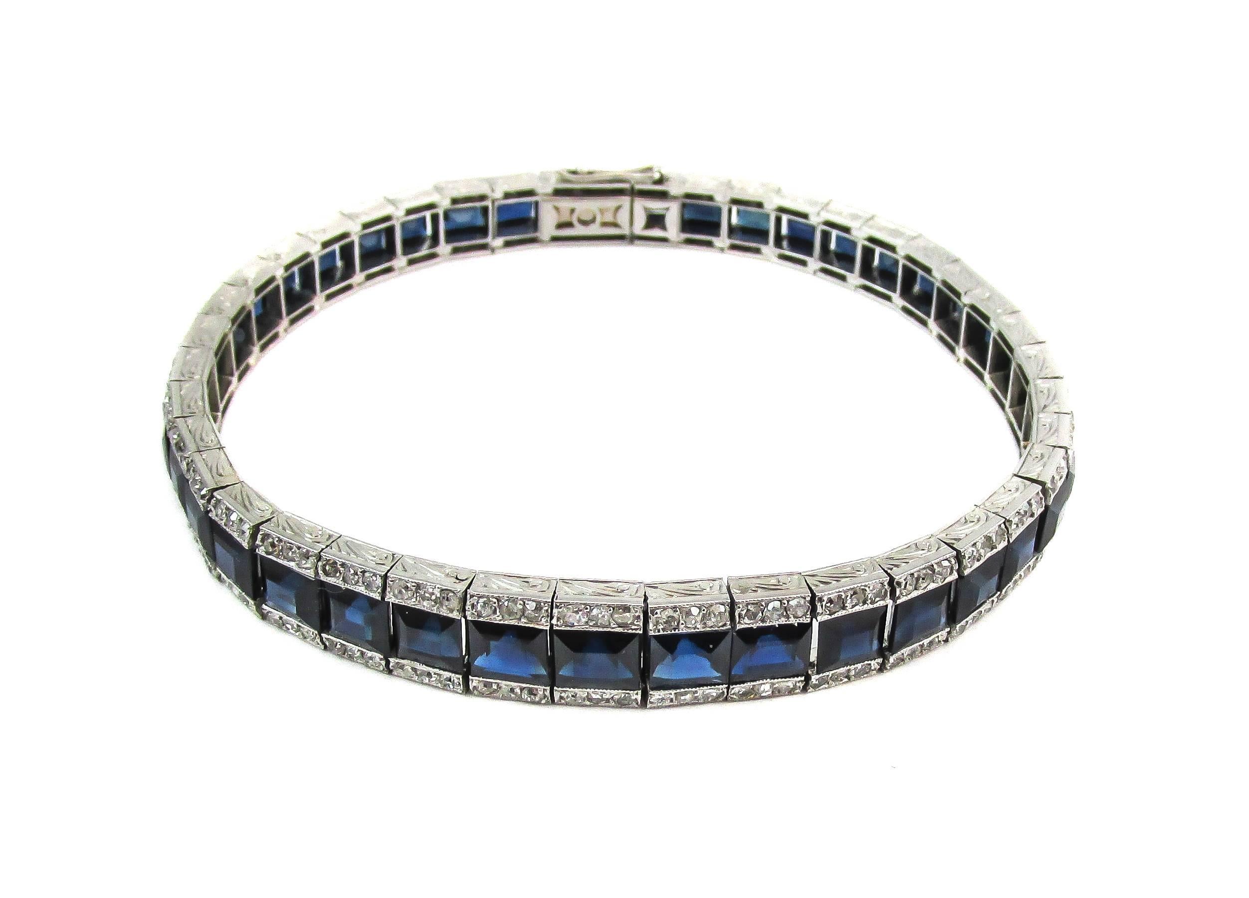 This elegant Art Deco platinum bracelet is centrally set with 41 rectangular deep blue step cut sapphires weighing approximately 20 carats. Bordering the sapphires, small round old cut diamonds are set on either side held within walls of beautifully