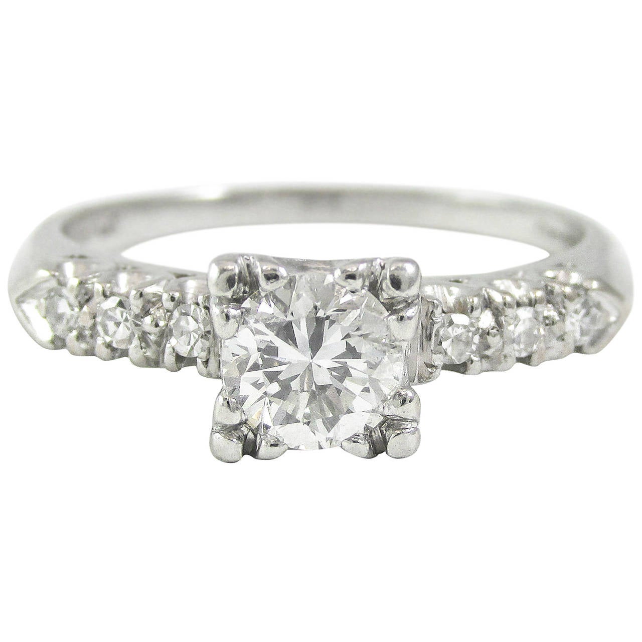 This wonderful diamond solitaire ring is set with a center transitional cut diamond weighing approximately 0.60 Carats. The diamond is set in a platinum mounting with finely detailed “fishtail“ prongs and 3 diamonds set along either side. The center