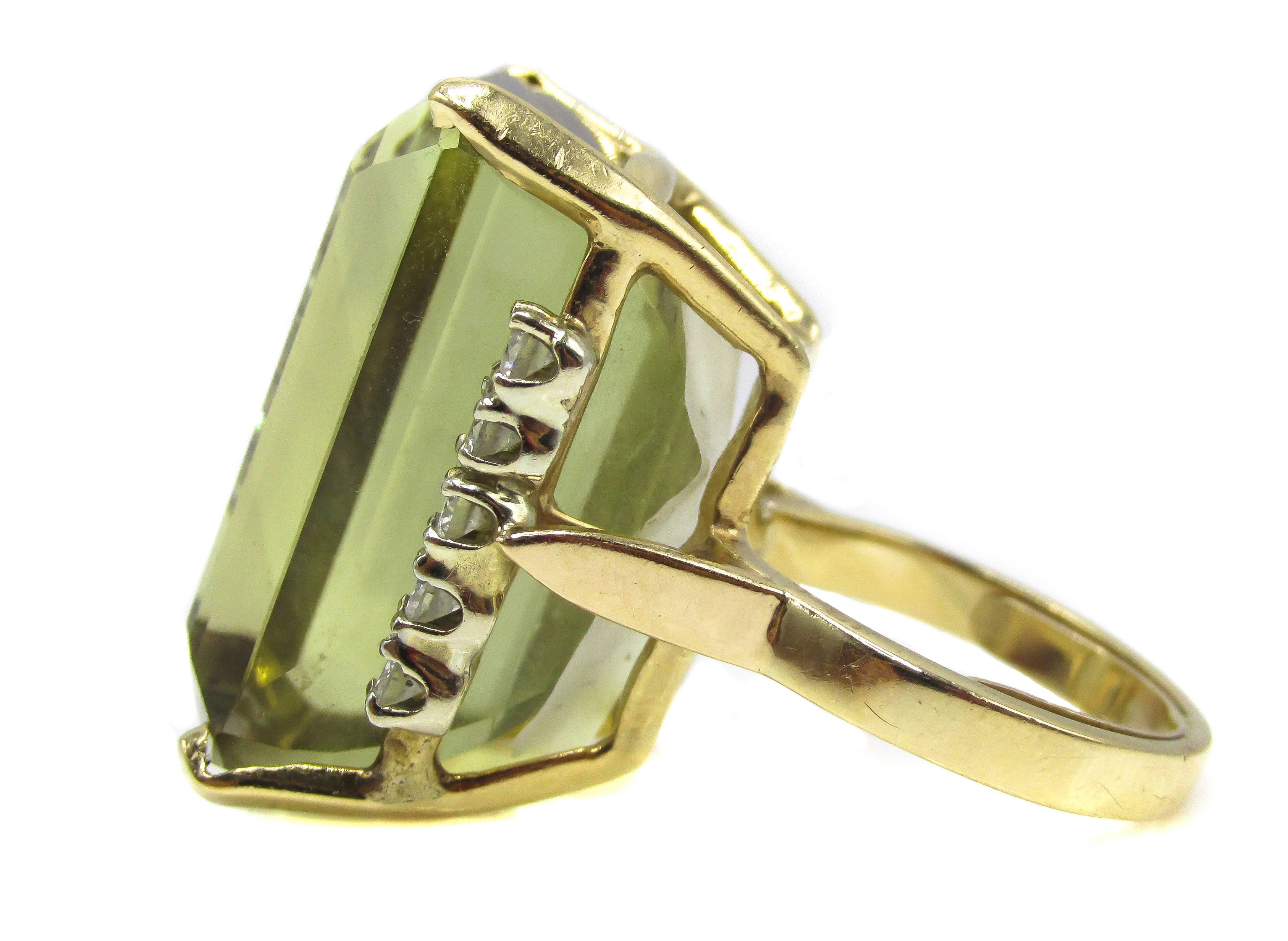 Impressive 1960’s 14 karat yellow gold ring with a greenish yellow citrine weighing approximately 40 carats. Each side of the center stone is embellished by 5 bright white round brilliant cut diamonds with a total weight of approximately 0.60