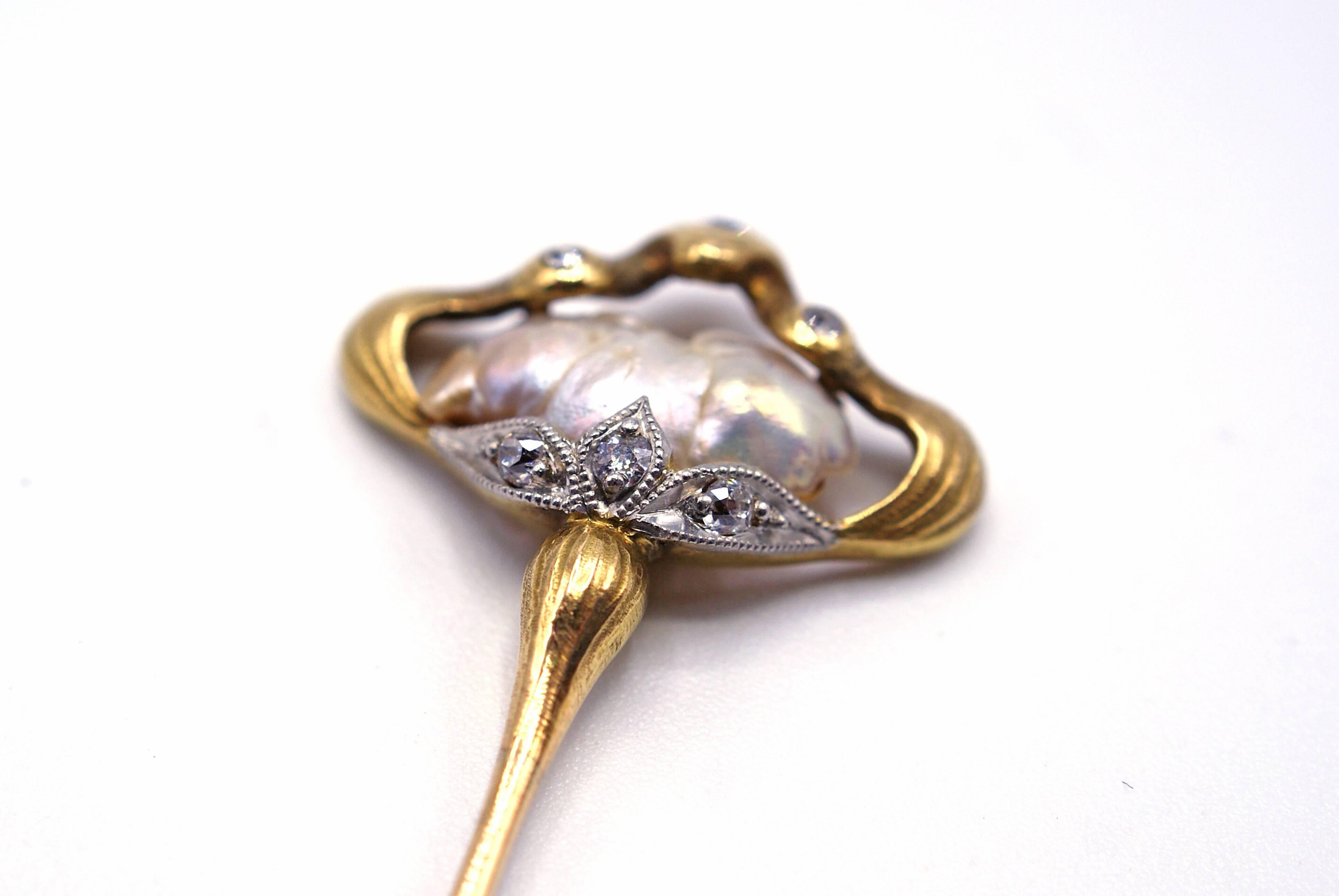 This lovely stick pin is finely handcrafted with a curved detailed gold frame surrounding a lustrous baroque pear. The frame is set with 3 small Old European Cut diamonds on the top and 3 more round diamonds at the bottom meeting the pin-stem. A