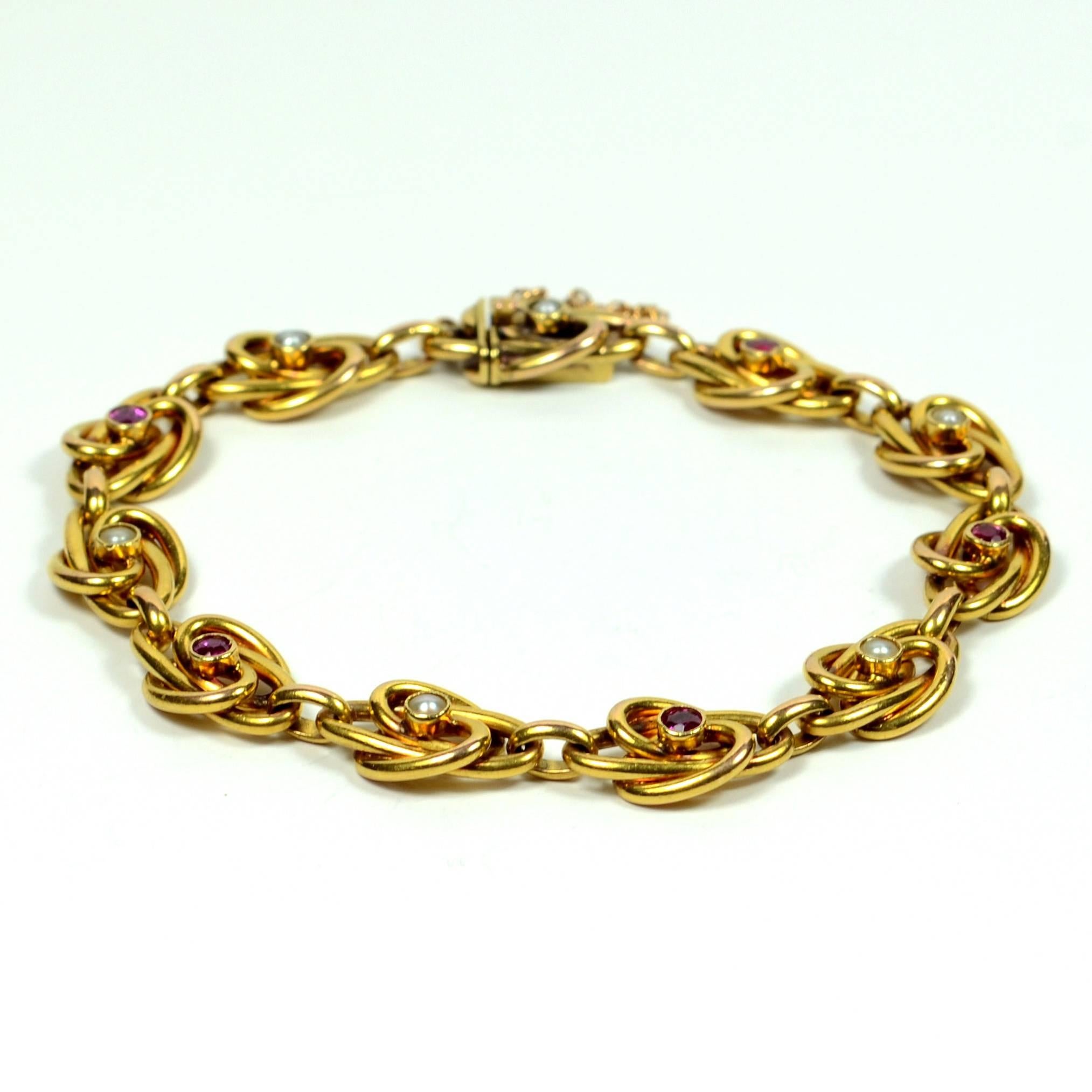 A lovely heavy 18 carat yellow gold link bracelet with scrolling links set alternately with natural pearls and rubies. The links have soft and flowing lines of gold that intertwine around each collet-set gemstone. 

The natural rubies are bright