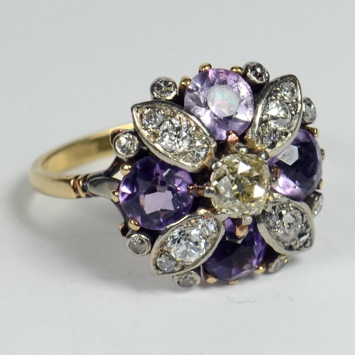 A charming flower ring in amethysts and diamonds set to the centre with a larger yellow toned old mine cut diamond. The four diamond petals are each set with three diamonds which range in size to complement the shape of the petals, and are