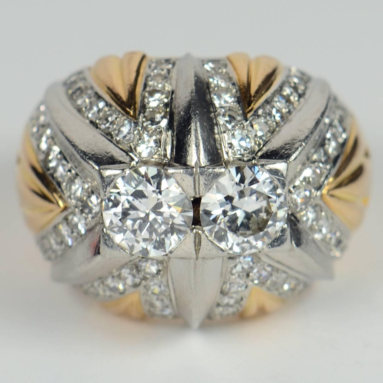 A very attractive French retro bombe ring of rounded design in 18 carat yellow gold with six ridges of platinum rising to hold two round brilliant cut diamonds (approximately 0.75 carats each) to the centre.  Each platinum ridge is outlined by