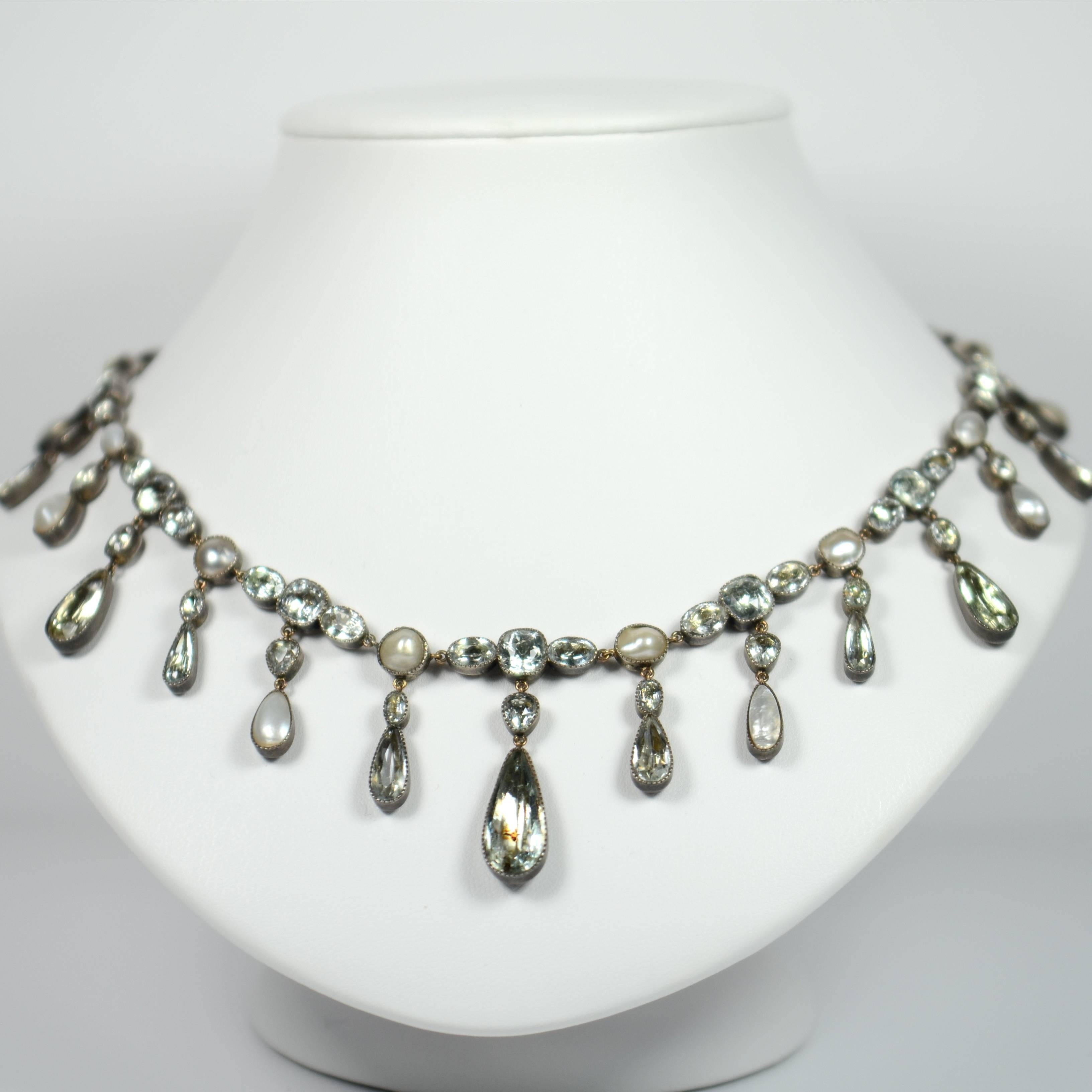 A rare and extremely pretty Georgian fringe riviere necklace with 63 foiled aquamarines and 18 blister pearls millegrain set to closed back silver mounts with a gold chain and toggle clasp. 

The graduated fringe pendant drops alternate between