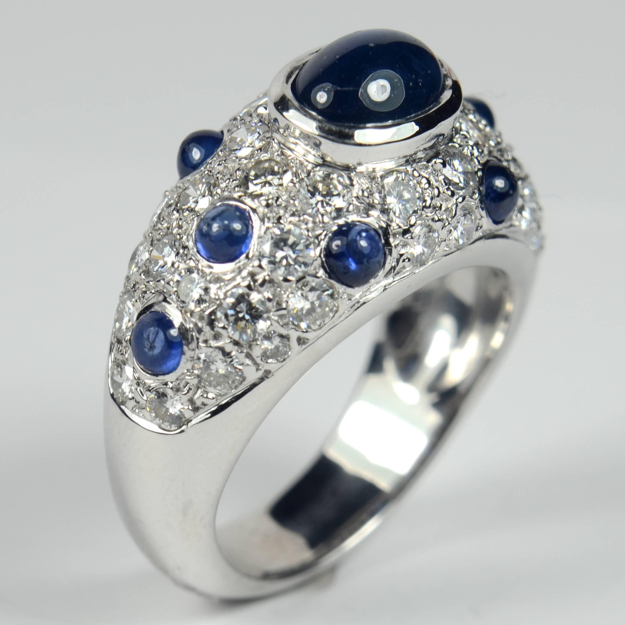 Made in 18 carat gold with rhodium plating, this ring is all curves. Set with 40 brilliant cut diamonds spotted with eight cabochon sapphires around a larger central sapphire weighing 2.08 carats, the design is strongly reminiscent of Suzanne