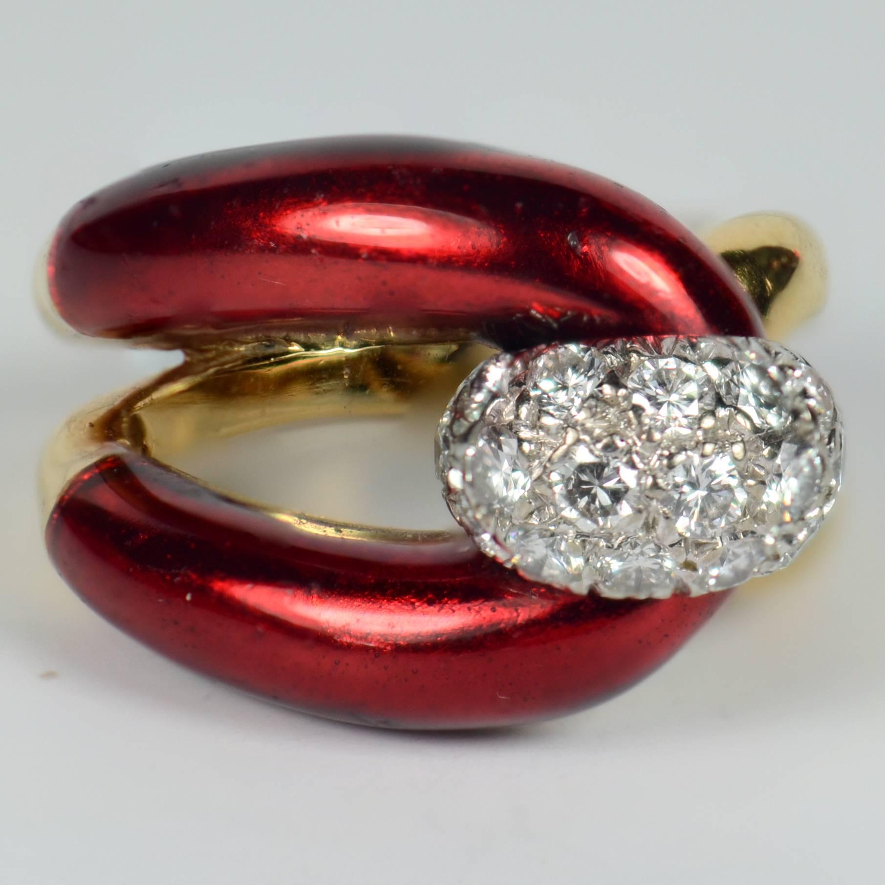 A very chic ring in 18 carat gold designed as a buckle, the uppermost part enamelled to a to a rich crimson. The bar of the buckle is represented by a diamond bombe finial in white gold pave-set with 16 round brilliant diamonds with a total