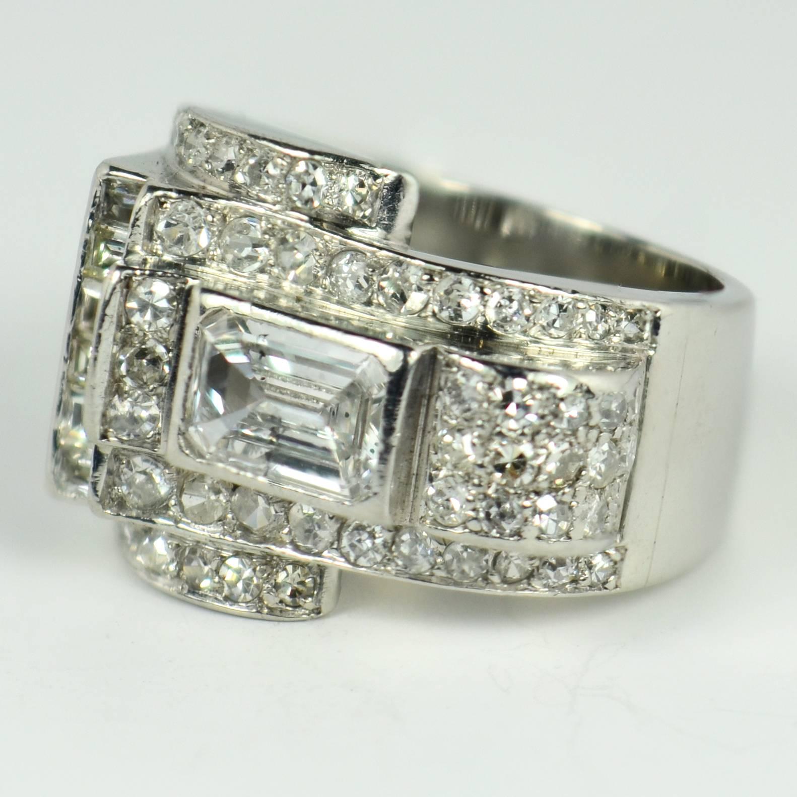 A French platinum and diamond ring with an asymmetric design and geometric form set with one emerald cut diamond weighing approximately 0.85 carats with F-G colour and SI2-P1 clarity due to a dark crystal inclusion to one side of the stone’s table. 