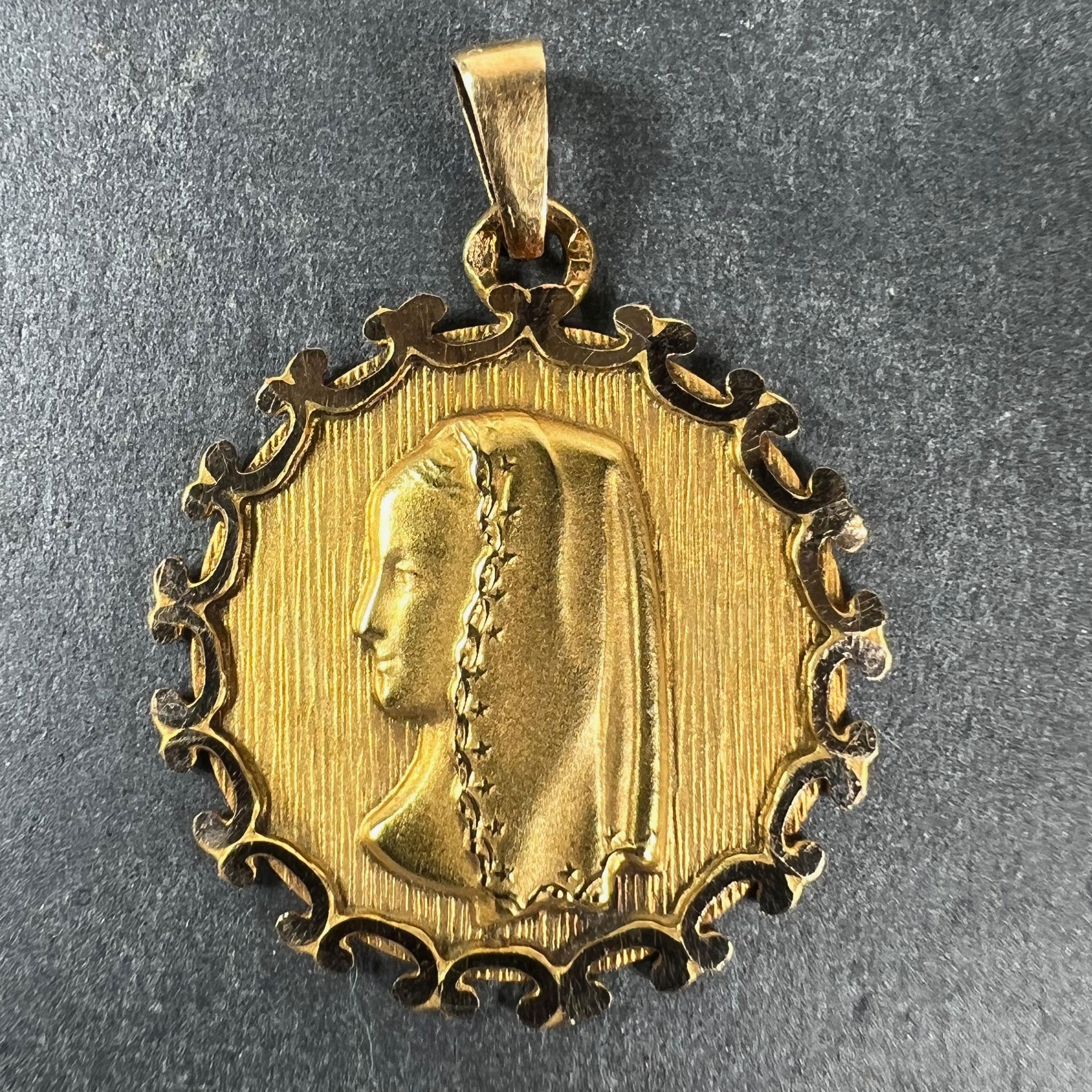 A vintage French 18 karat (18K) yellow gold pendant designed as a round medal with polished and ridged petal edges depicting the Virgin Mary in profile wearing a veil. Stamped with the eagle’s head for French manufacture and 18 karat gold, with an