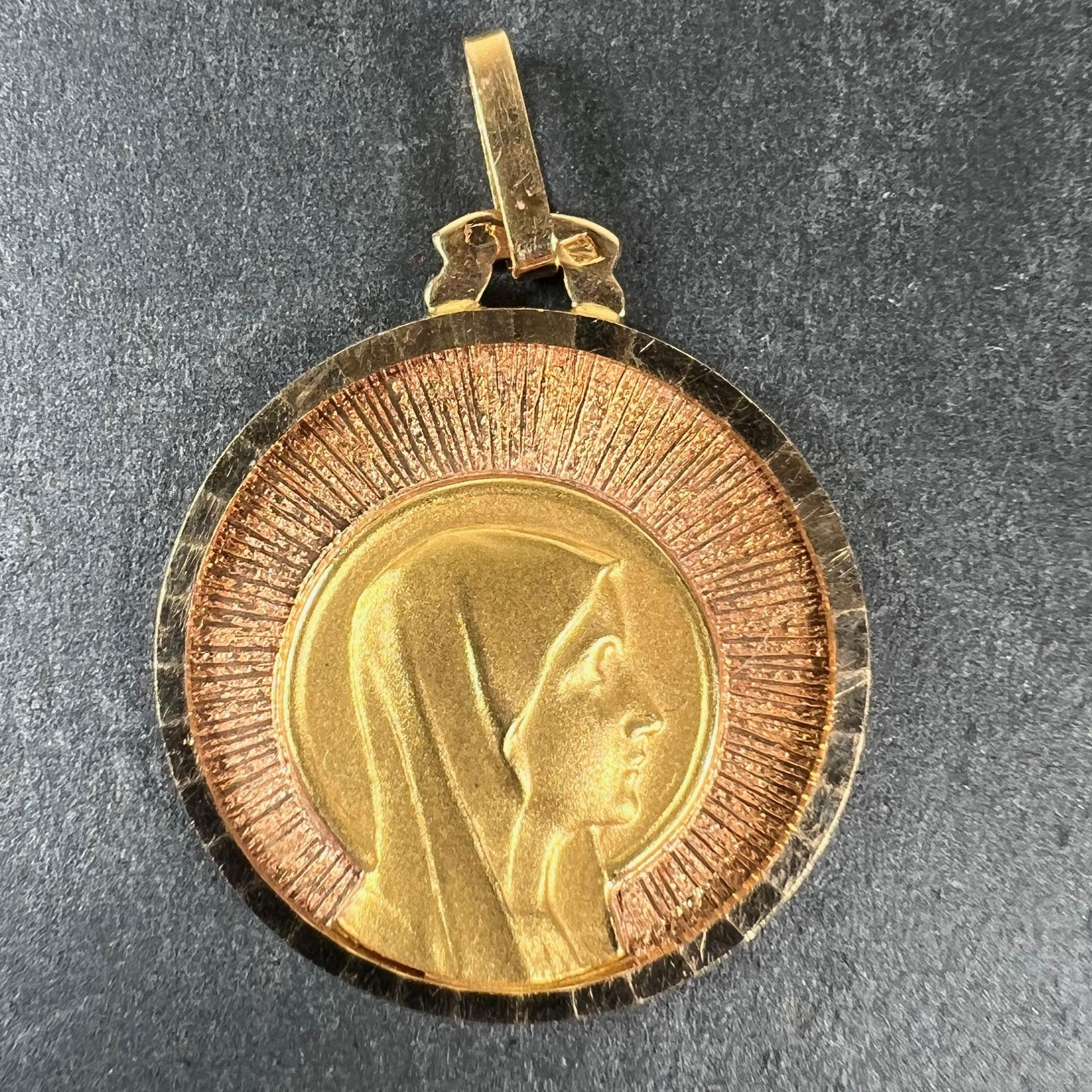 A vintage French 18 karat (18K) yellow and rose gold pendant designed as a round medal depicting the yellow gold Virgin Mary with halo in profile against a rose gold sunburst ground. Stamped with the eagle’s head for French manufacture and 18 karat