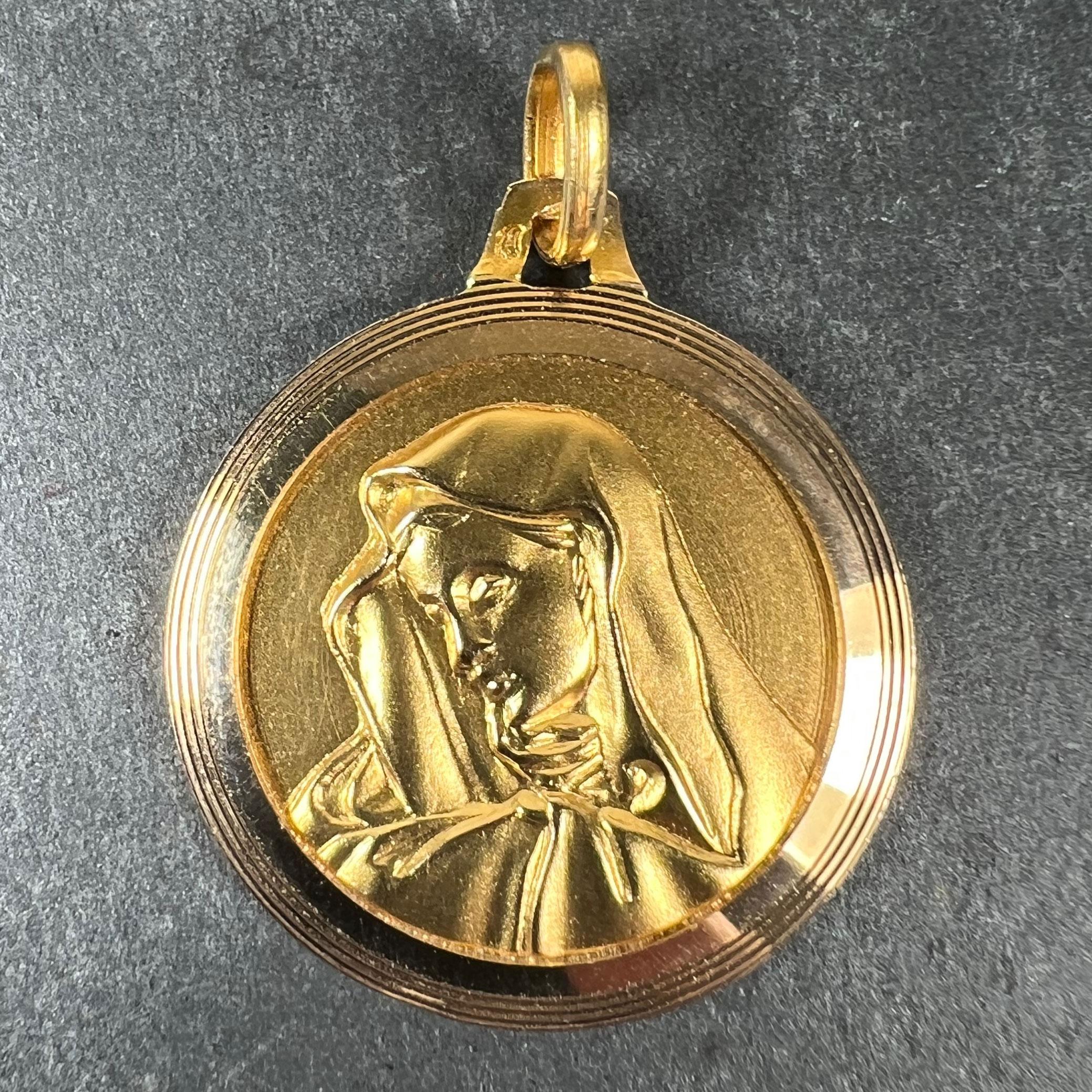 A vintage French 18 karat (18K) yellow gold pendant designed as a round medal depicting the Virgin Mary with an engraved frame. Stamped with the eagle’s head for French manufacture and 18 karat gold, with an unknown maker’s mark.

Dimensions: 2.6 x