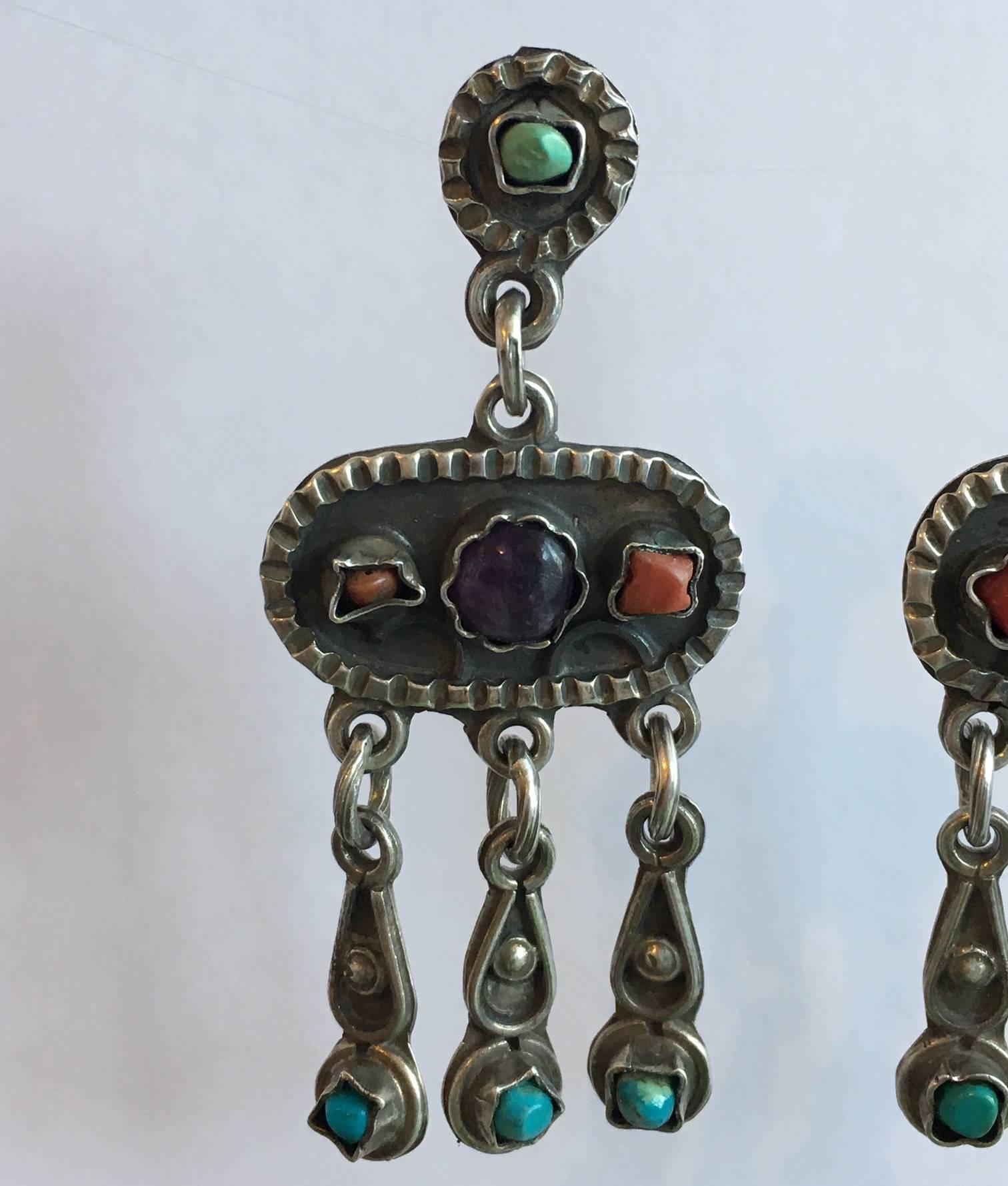 The bold design of this handcrafted pair of earrings embodies the essence of a trip to Mexico. Set with amethyst, turquoise and coral, they are colourful and eye-catching. The design is pleasingly articulated with a stylish bohemian edge that offers