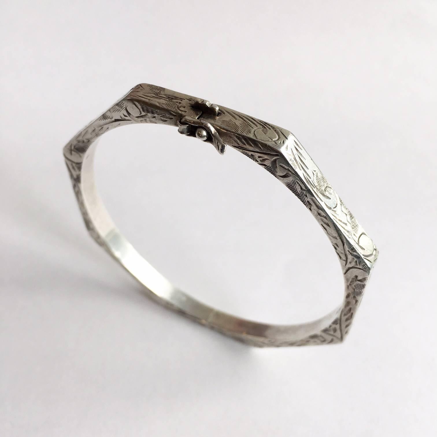 This stylish silver bangle is a bit different with its octagonal shape. The surface is etched with a delicate, stylised foliate design. It opens with a catch and hinge, so getting it on and off is no trouble. The closure has a satisfying click. It