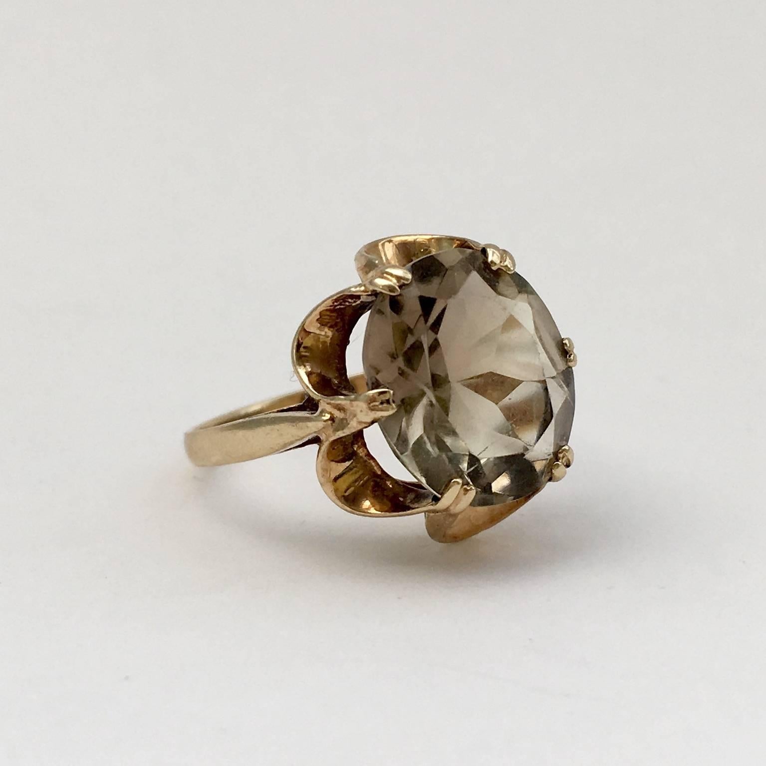 The stylish design of this 9ct gold ring is typical of its era. It combines smoky seventies hues with a lovely scalloped flower setting, no doubt inspired by nature. The faceted gemstone perches high on its arched mount, giving the ring a beautiful
