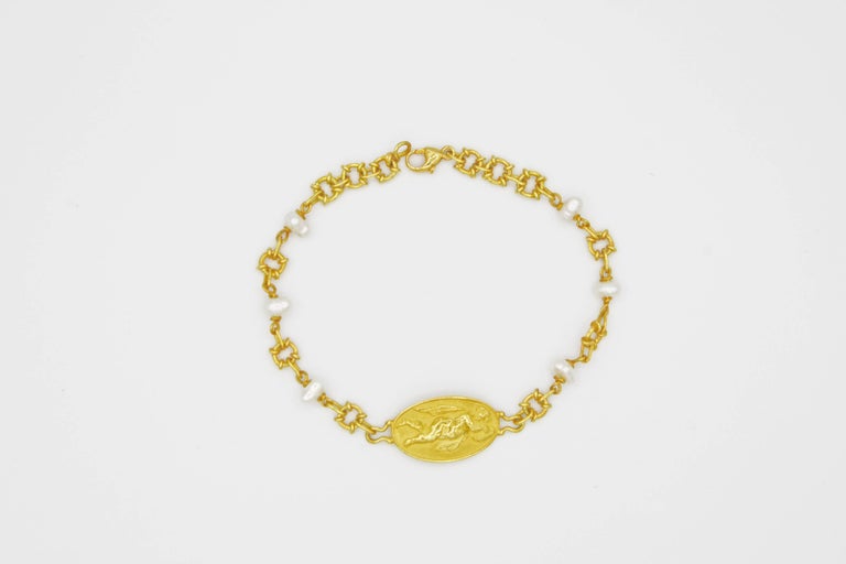 This ethereal 18k gold link bracelet is a piece from Renato Cipullo's Romantica Collection.  The bracelet is comprised of a cupid medallion joined with elaborate loops as well as petite freshwater pearls.