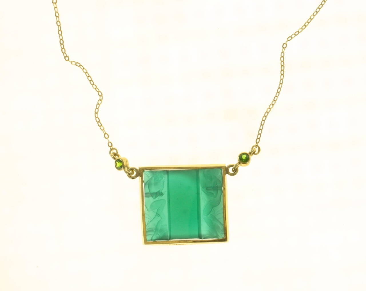 Original Antique Art Deco Emerald green glass pendant set in 18kt gold with
two round cut Emeralds
Chain measures 16 1/2 inches
Center glass panel measures 1 inch by 3/4 inch
