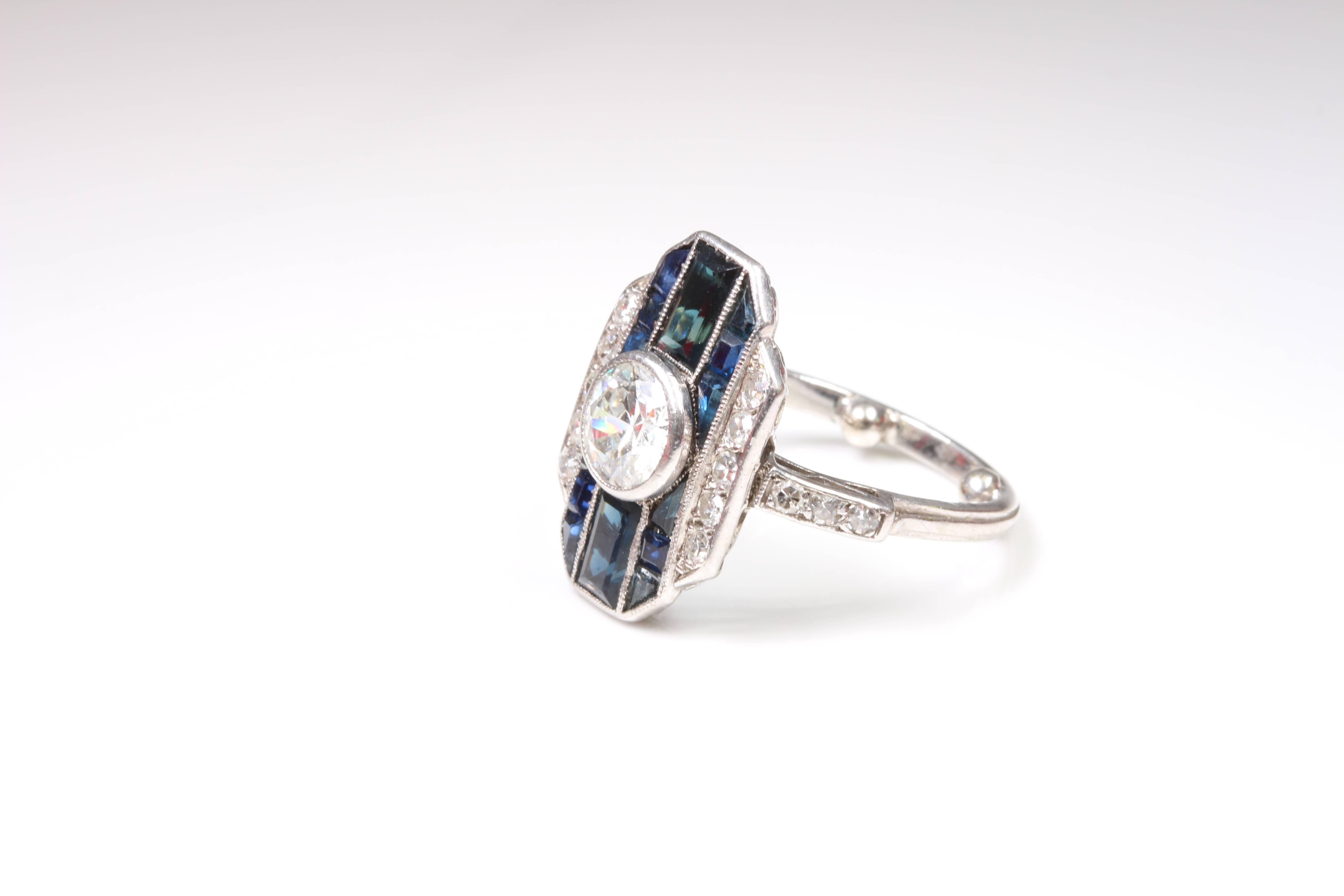 Original art deco platinum sapphire and diamond dress ring. Sleek, crisp and stylish and so very deco! Centre early modern brilliant cut diamond of 0.75ct I/SI bezel set with 2 rectangle cut sapphires and 12 fancy cut sapphires. A further 10 side